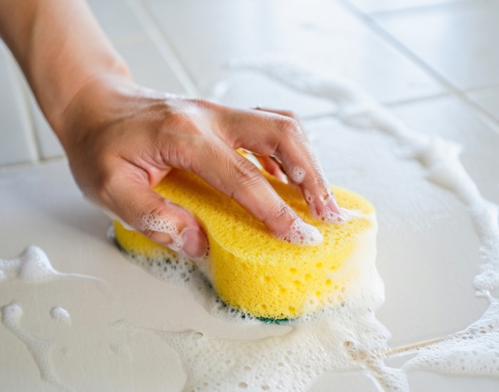 Mano limpiando los azulejos de la cocina con un paño de microfibra